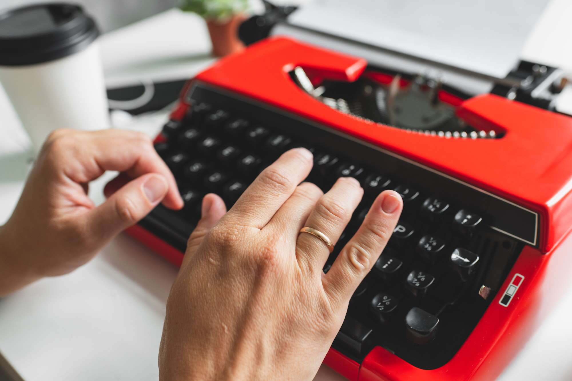Woman hand working with bright red vintage typewriter