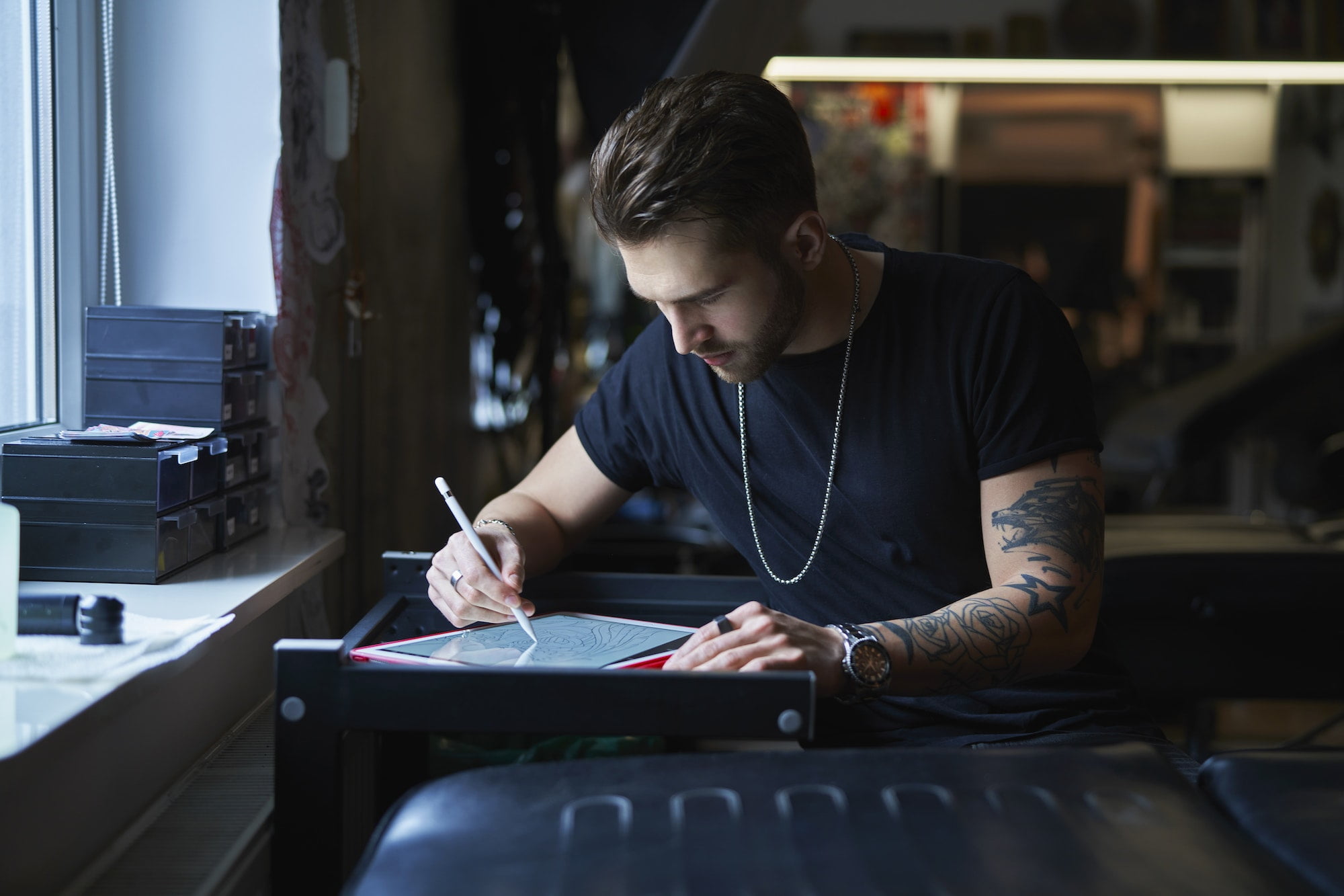 Caucasian tattoo artist designing motifs on digital tablet